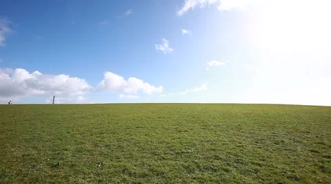 Man walking on the edge of a green hill with beautiful clouds above, Stock Footage 48824480