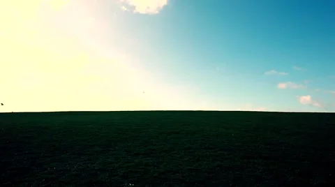 Man walking on the edge of a green hill with beautiful clouds above Stock Footage 48825501