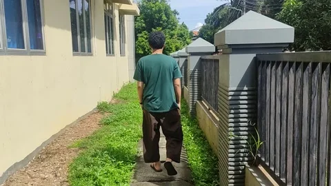 A Man Walking on Footpath next to Abandoned Building Stock Footage 234804639