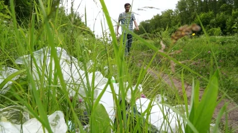 A man walking in the forest drinks and throws away his empty bottle Stock Footage 133445159