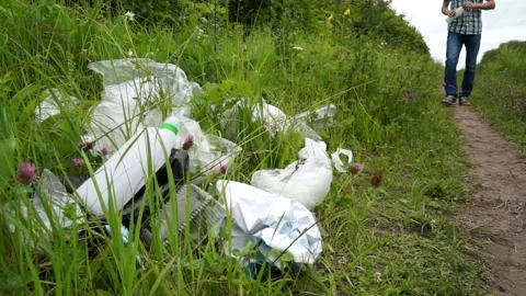 A man walking in the forest drinks and throws away his empty bottle Stock Footage 133445165