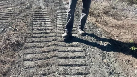 Man walking forward, turns around, field on bulldozer tracks Stock Footage 222982614