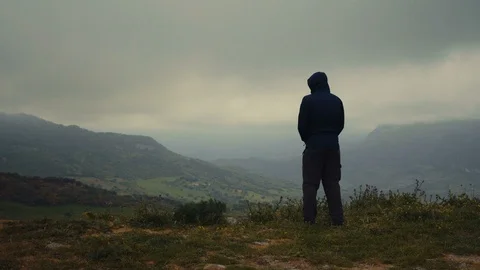 A man walking into frame with mountains in the background Stock Footage 88719862