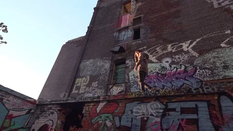 Man Walking on Graffiti Abandoned Building Roof Top Stock Footage 82353012
