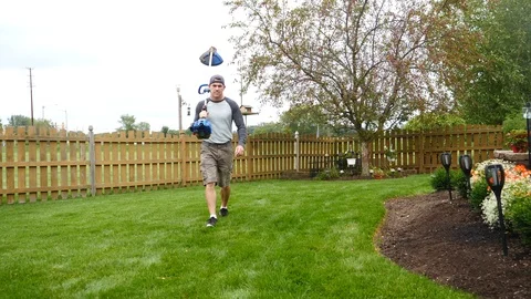 Man walking with grass trimmer across the yard lawn, 4k, 60fps. Stock Footage 115849478