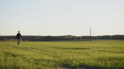 Man walking on green field Stock Footage 128987266