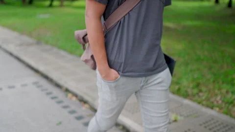 Man is walking with his hands in his pants and holding a laptop  Stock Footage 283186802