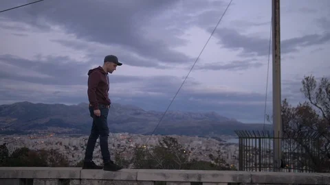 Man Walking on Ledge During Dark Stormy Day in Croatia with Blue Tones Stock Footage 90662288