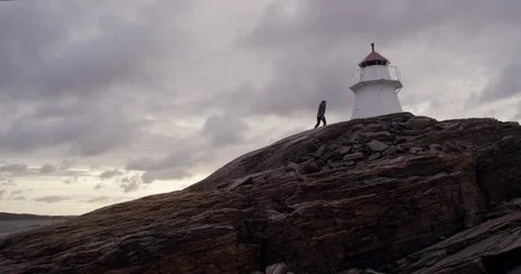 Man walking up a limestone rock to a lighthouse. Stock Footage 106121616