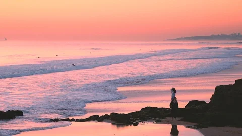 Man walking in low tide, sunset sky reflections on water at Carcavelos beach Stock Footage 108918234