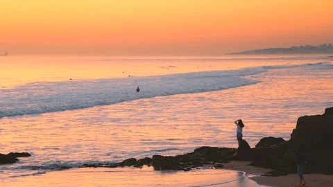 Man walking in low tide, sunset sky reflections on water at Carcavelos beach Stock Footage 108918862