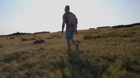 Man walking in meadow at sunset on Stock Footage 127840874