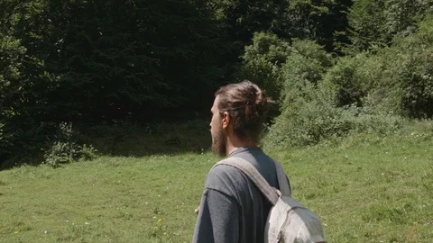 Man walking on a meadow surrounded with trees and suddenly turns around Stock Footage 121806845