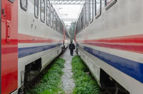 Man walking in the middle of two trains Stock Photos