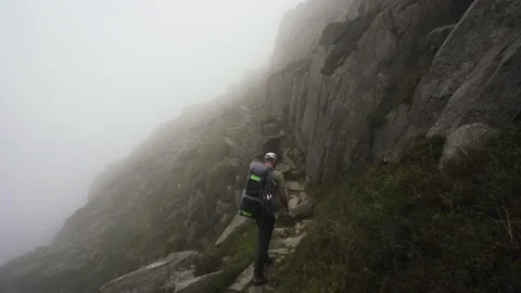 A man walking a misty mountain trail in windy weather Vídeo Stock 141663068
