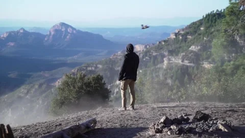 Man walking to a mountain ledge, looking at dust, a bird and a scenic, Stock Footage 148806187