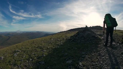 A man walking a mountain summit placing a rock on a cairn Video stock 164109625