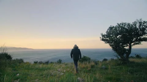 A man walking in the mountains and looking out to the sea at dawn. Montenegro. Stock Footage 273296214