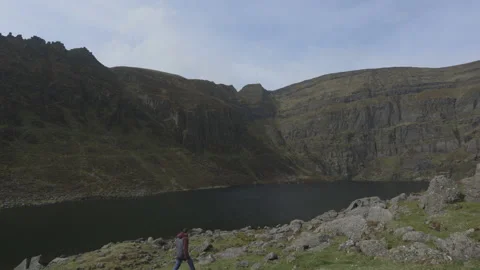 Man walking in the mountains around a lake Vídeos de archivo 153855683