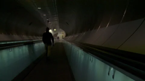 Man walking on moving sidewalk. Smooth tilt up dolly shot of futuristic tunnel Stock Footage 42490776