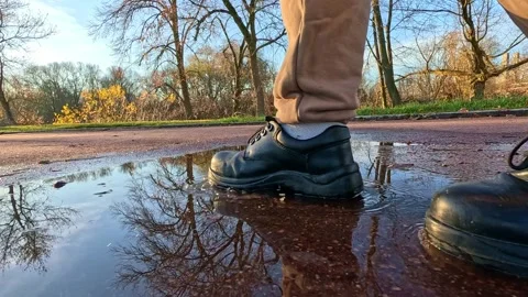 Man walking near puddle with close-up boots motion Stock Footage 321892540