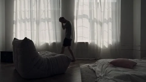 Man walking nervously back and forth in dark room, struggling with anxiety and Stock-Footage 310876894
