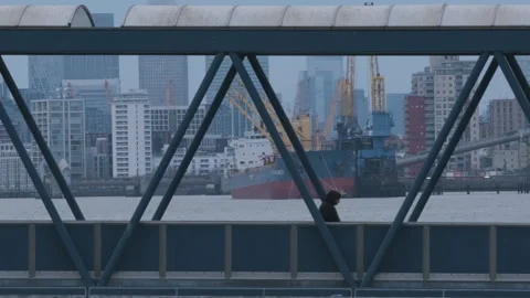Man Walking Over Bridge with River Thames Industry, Cargo Ship and Stock Footage 222106975