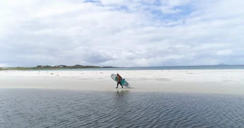 Man walking with paddleboard on beach Stock Footage 85961997