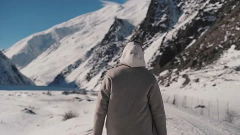 A man walking in the path between mountains turning around to face the camera Stock Footage 169813304