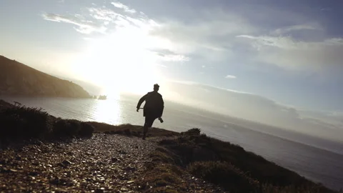 A man is walking on a path near the ocean Stock Footage 298262713