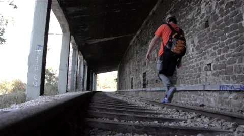 Man walking on a railway track at the exit of a tunnel  Stock Footage 59841557