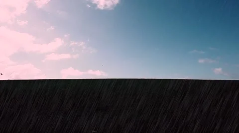 Man walking in rain on top of green hill with clouds Stock Footage 48825823