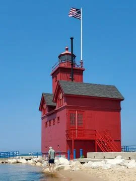 Man walking by red lighthouse Stock Photos