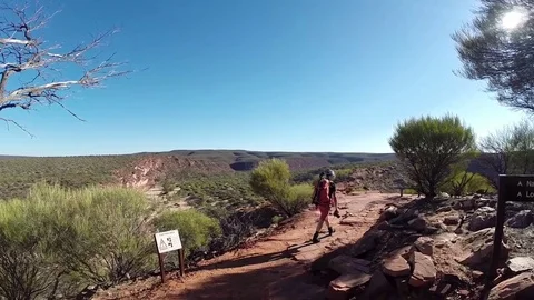Man walking on red rocks over almost dry Murchison River bed in Kalbarri NP Stock Footage 70968441