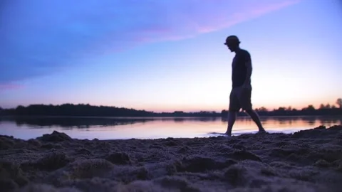 Man walking from right to left through beautiful sunset at beach Stock Footage 146268580