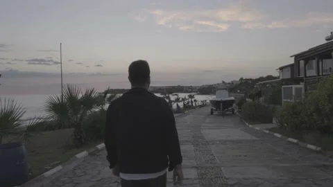 Man walking on the road by the sea log video Stock Footage 229996015