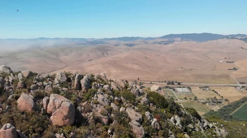 Man walking up rocks to the top of Mountain Peak with Fog in the Distance Stock Footage 128274932