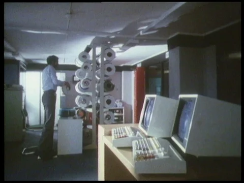 Man walking in room with computers with roll of spare paper for receipts, 1985 Vidéo 136674186
