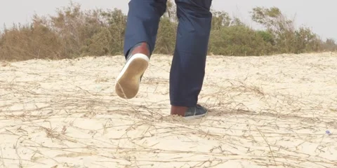 Man walking up a sand dune in at a beach in Senegal 4k slow motion Stock Footage 277120430
