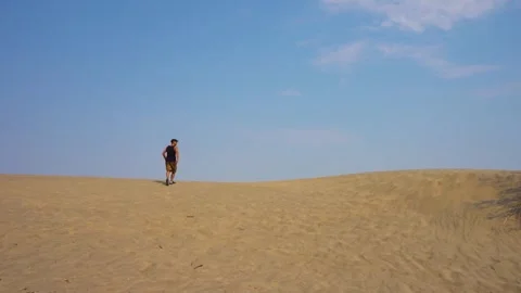 Man walking on a sand dune in a desert Stock Footage 276828649