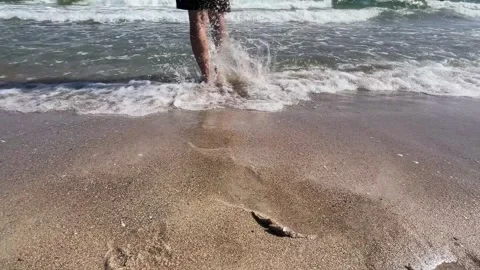 Man walking on sandy beach entering the sea Stock Footage 329319826