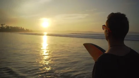 Man walking on sandy beach holding longboard sunset rapid slow motion Video stock 84823780