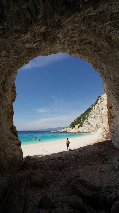 Man walking from sea cave toward Platis Ammos Beach, Ithaca Island, Vertical 動画素材 309093276