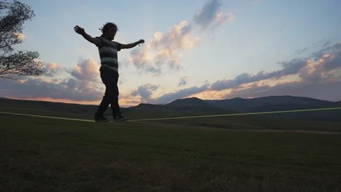 Man walking on slack line at sunset Stock Footage 121868504