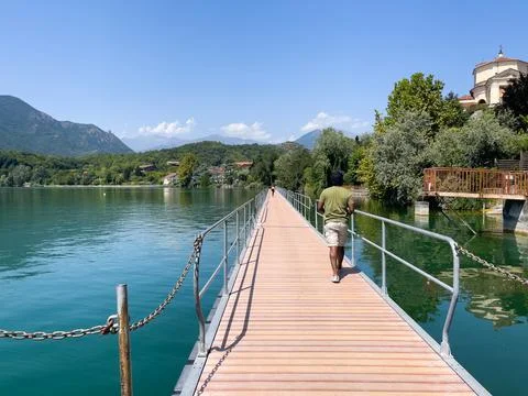 Man walking on a small bridge over a lake in Italy Stock Photos