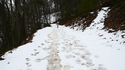 Man walking up a snow covered trail in the mountians Stock Footage 53860010