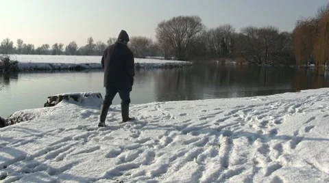 Man walking in the snow by a river. Stock-Footage 10745132