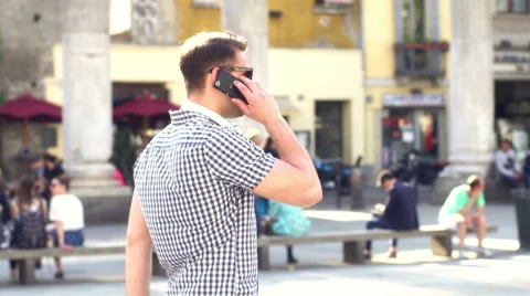 Man walking on the square and talking on the phone, steadycam shot 스톡 동영상 56036075