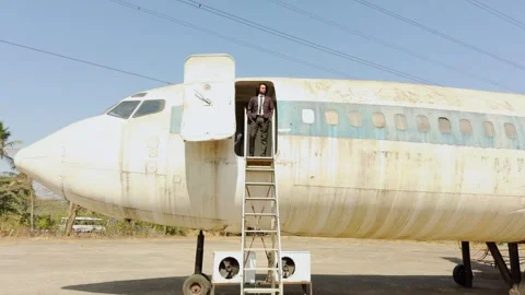 Man walking standing on plane door and looking or descending a ladder from .. Stock Footage 270195156