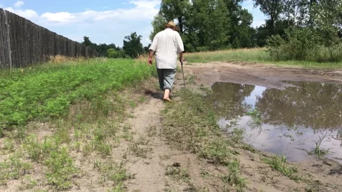 Man with walking stick passing carefully by big puddle on country roadkraine 스톡 동영상 163717170